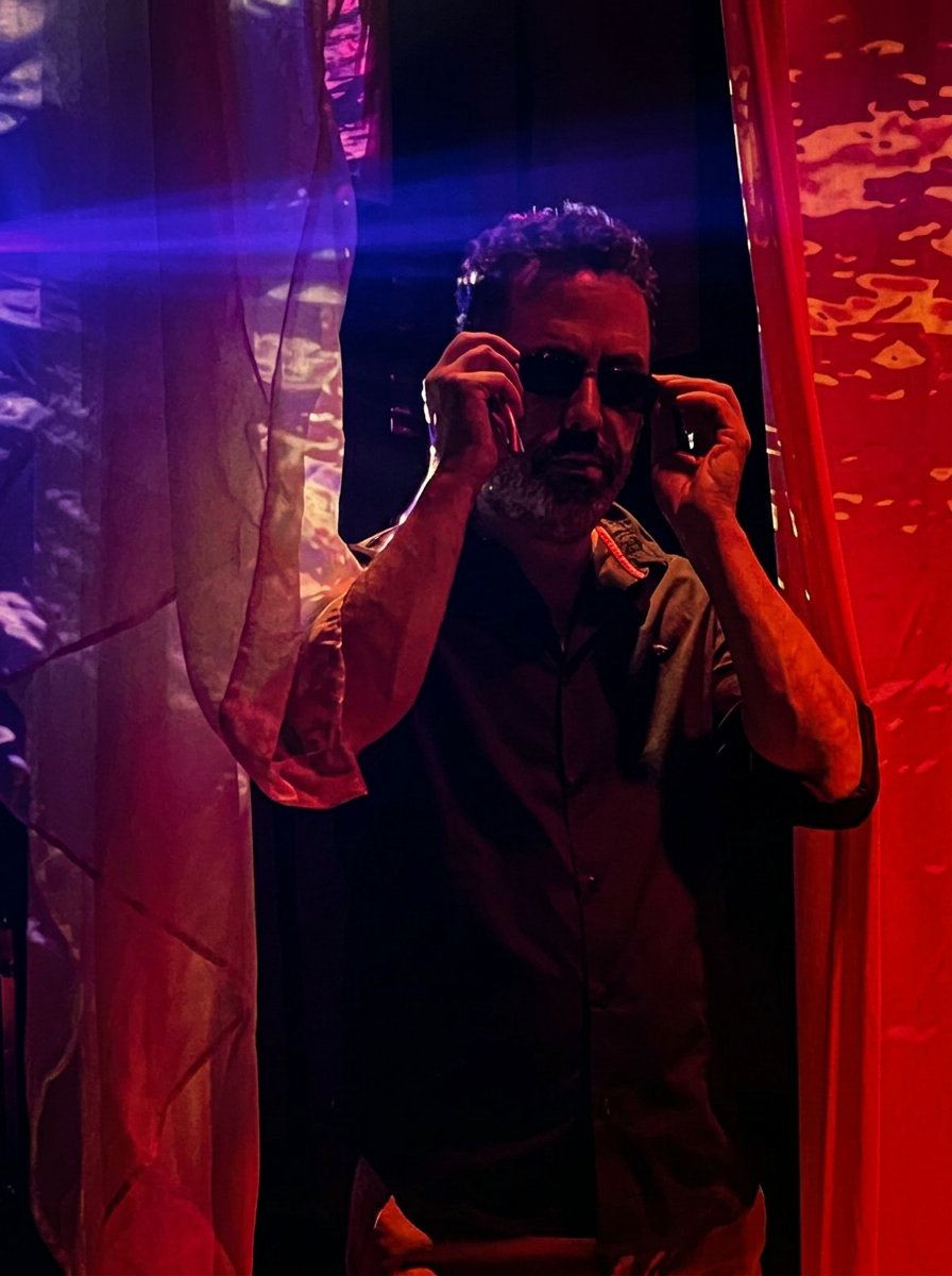 Yoel between red and blue neon curtains at a club